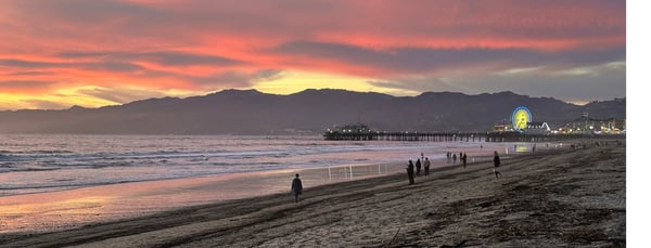 A sunset at Santa Monica Beach, the pier in the background, fire debris on the sand.