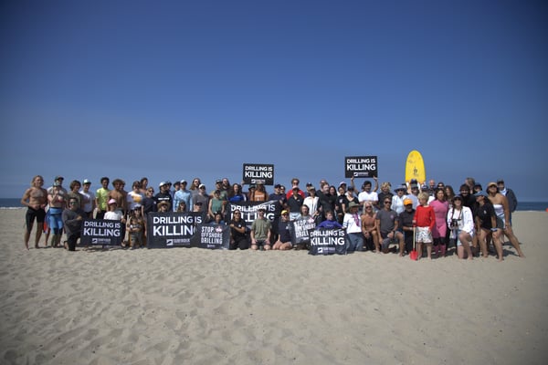 People on the beach opposing offshore drilling before paddle out