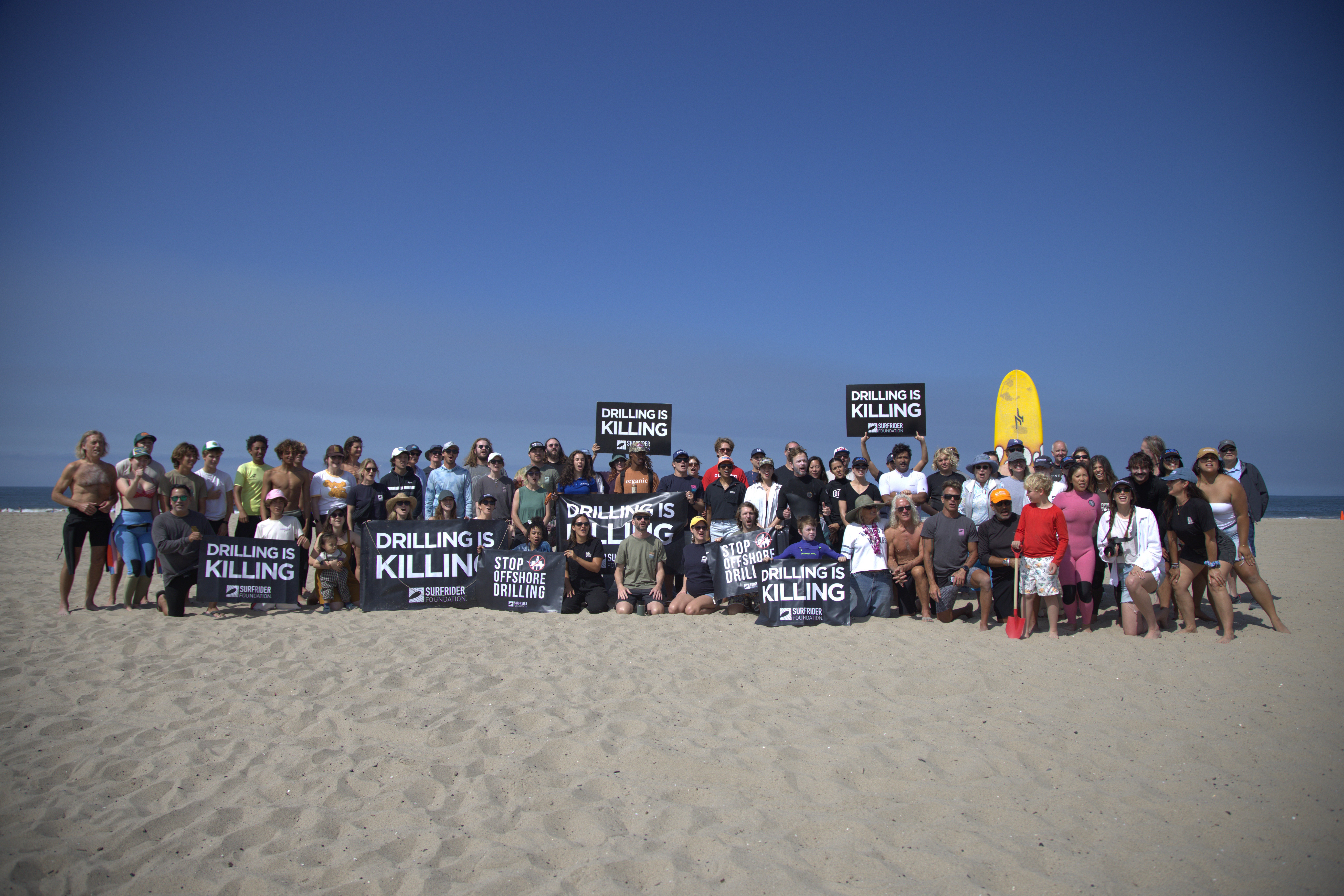 People on the beach opposing offshore drilling before paddle out